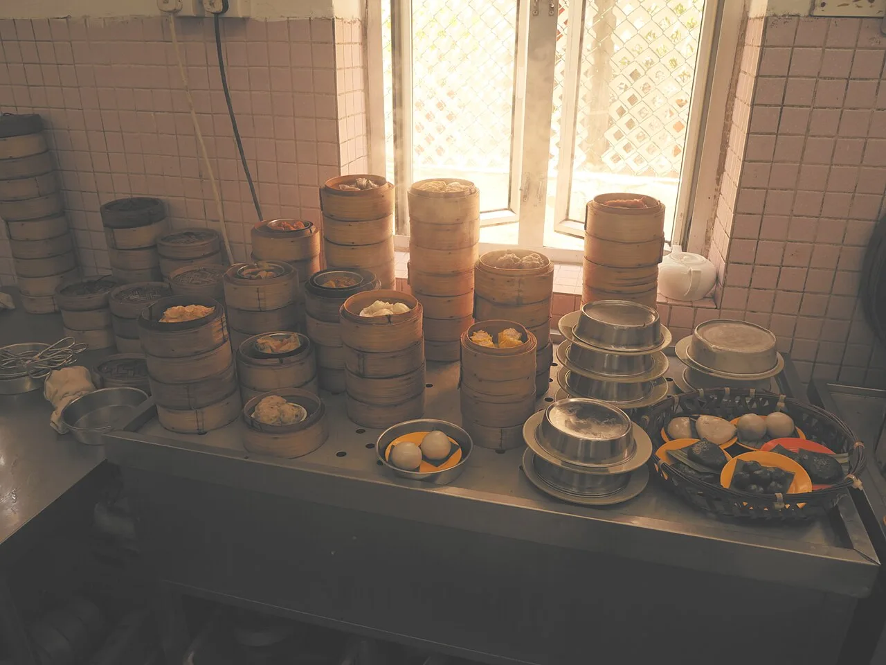 Bamboo steamers filled with Cantonese dim sum beside a sunlit teahouse window.