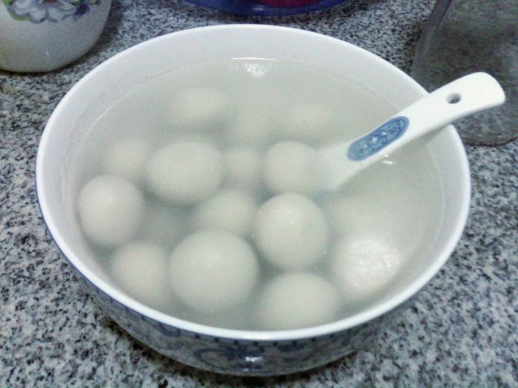 White tangyuan rice balls served in a porcelain bowl.