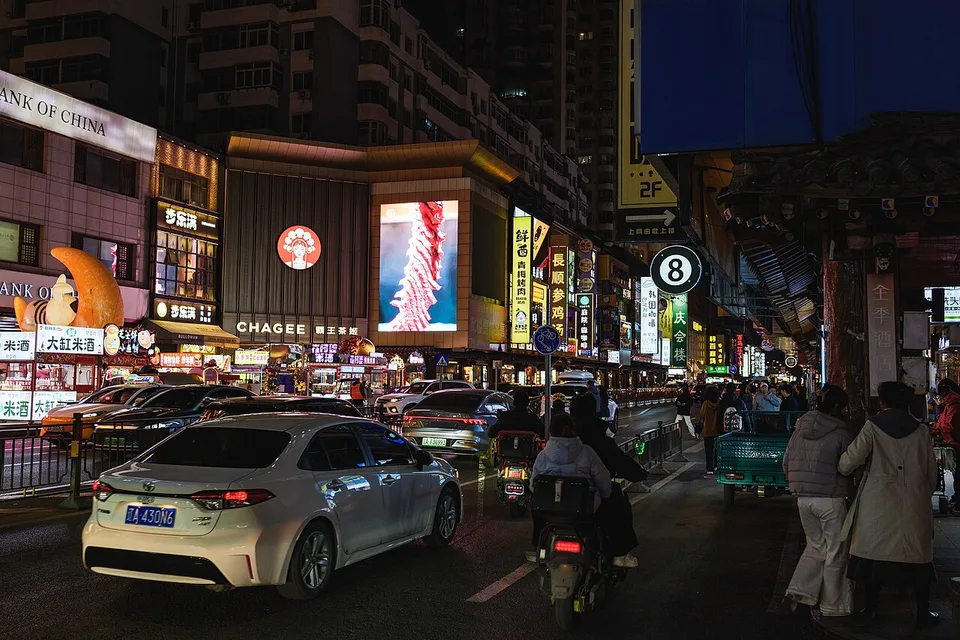 Illuminated restaurant signs and storefronts on Xita Street at night.