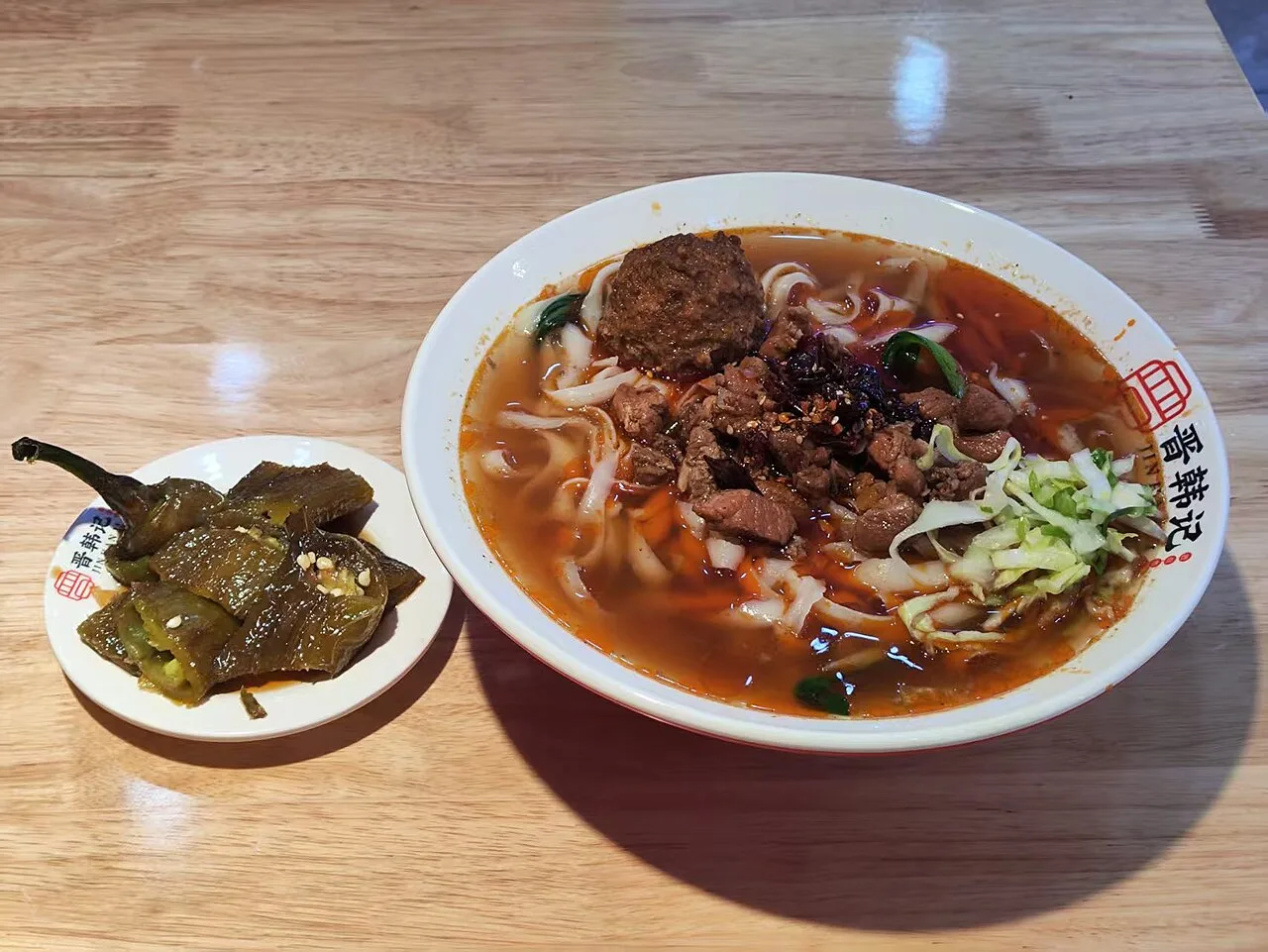 A bowl of broad knife-shaved noodles with broth and toppings.