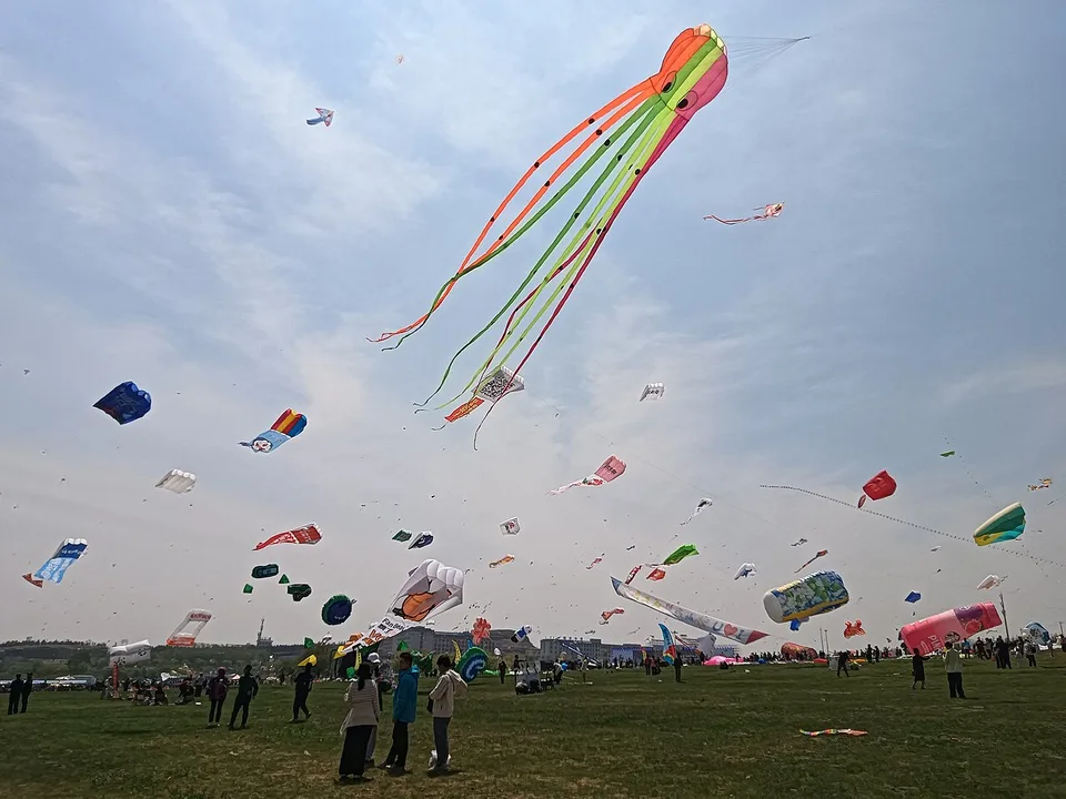 Colorful long-tailed kites above visitors at the Weifang International Kite Festival.